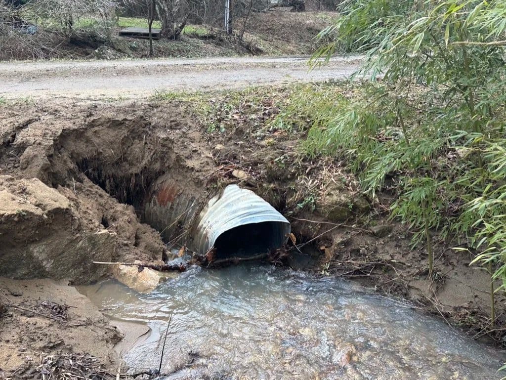 Storm water washed the fill out from around a culvert pipe under a gravel road.