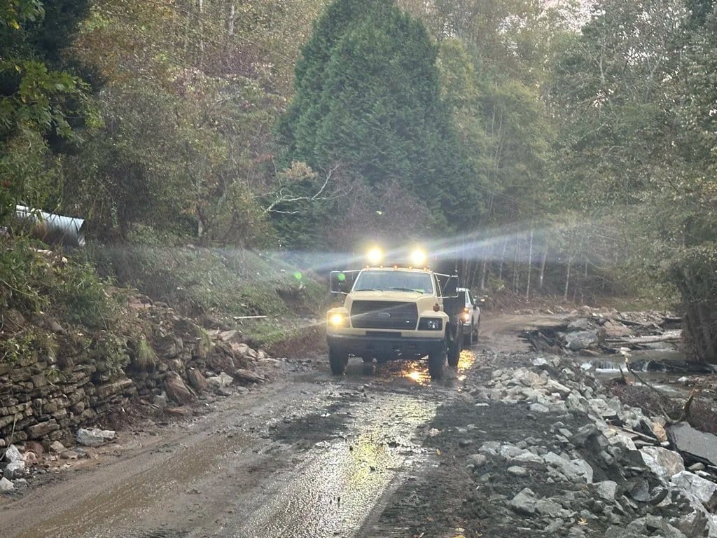 A truck working its way up a mountain road torn apart by storm water.